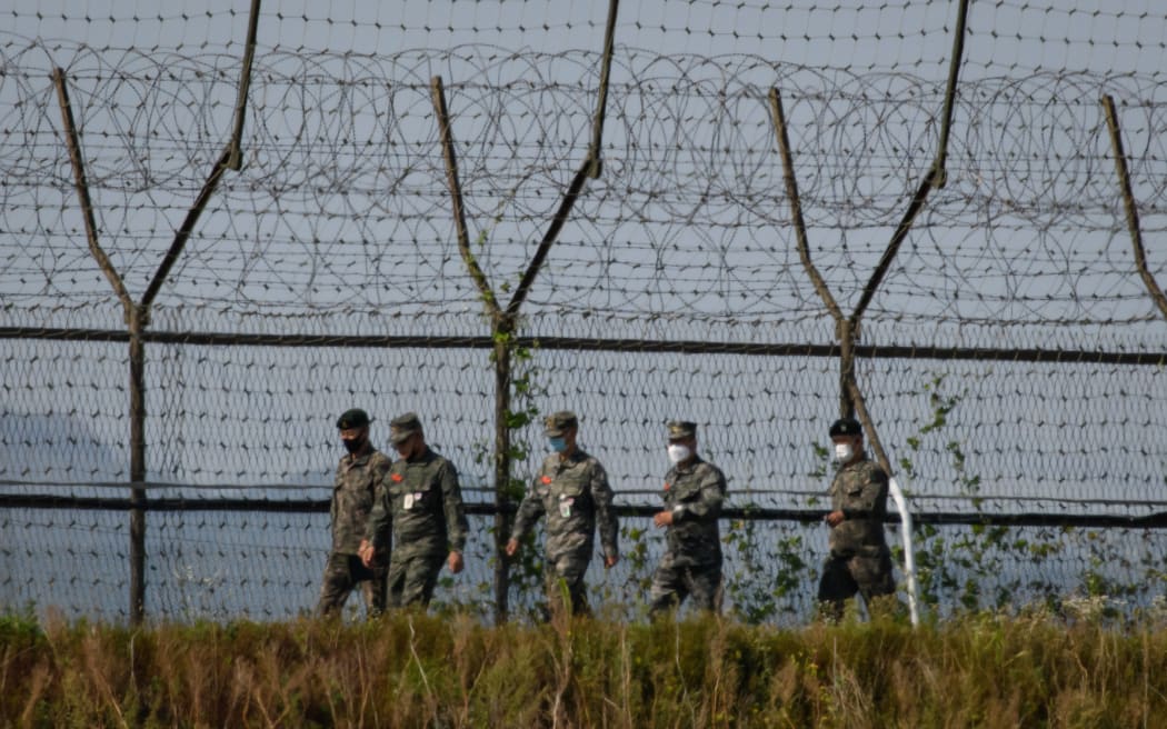 South Korean soldiers walk along a fence of the Demilitarized Zone (DMZ) separating North and South Korea, on the South Korean island of Gyodong on October 6, 2020. (Photo by Ed JONES / AFP)