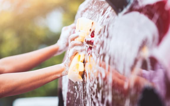 Man washing red car with sponge and soap