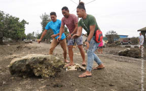 Residents at Patangata Settlement in the capital Nukua'lofa clear boulders from the seafront road.