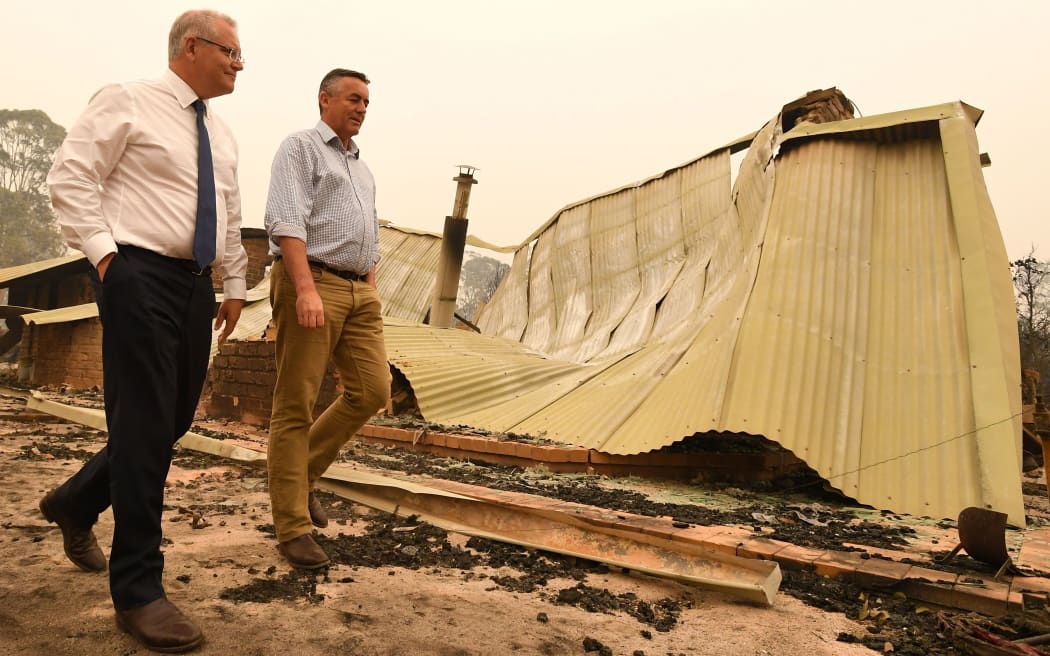 Australia's Prime Minister Scott Morrison (L) and MP Darren Chester visit a resident's property in an area devastated by bushfires in Sarsfield, Victoria state on January 3, 2020. -