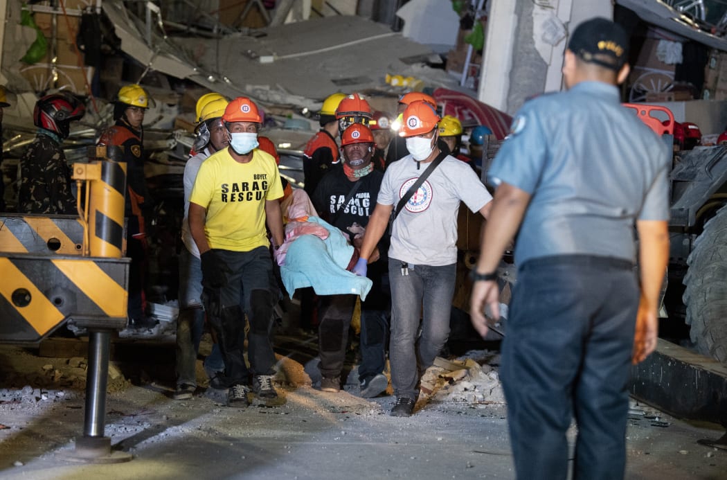 Rescue workers carry victim from a collapsed Chuzon Super Market in Porac, Pampanga, after a powerful earthquake hit northern Philippines on April 22, 2019.