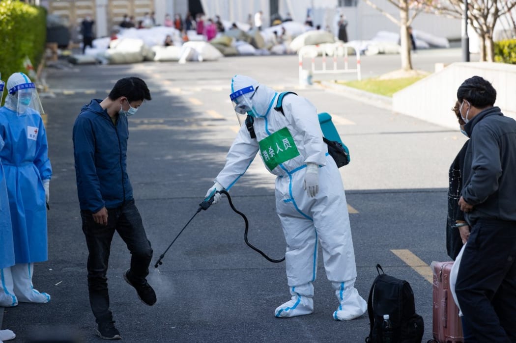 A patient who has recovered from COVID-19 receives disinfection before leaving a makeshift hospital converted from Shanghai Convention & Exhibition Center of International Sourcing in Shanghai, east China, April 9, 2022.