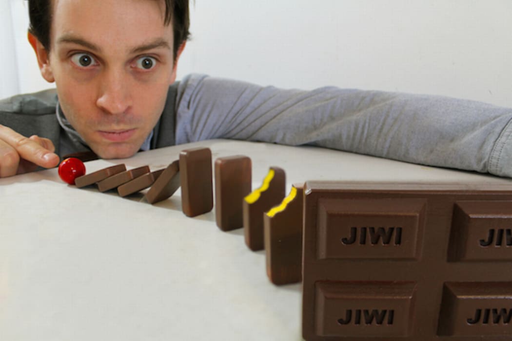 An Image of Joseph Herscher in the role of Jiwi as he tests the chain reaction abilities of a line of chocolate bars.