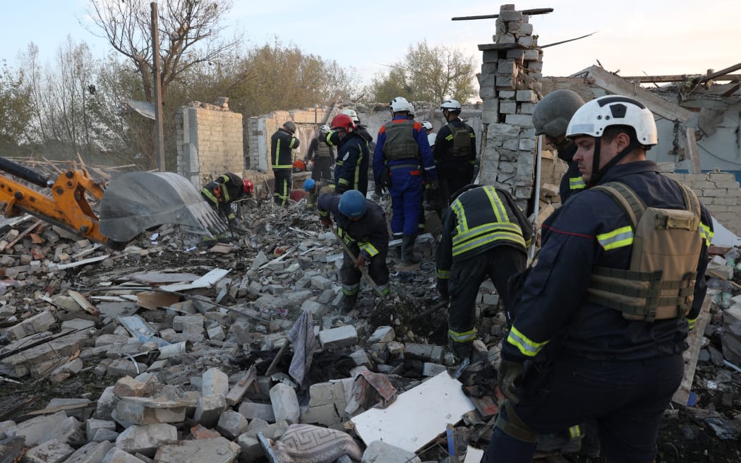 Ukrainians work outside the rubble of a cafe destroyed by a Russian missile attack in the village of Hroza in eastern Ukraine killing at least 51 people.
