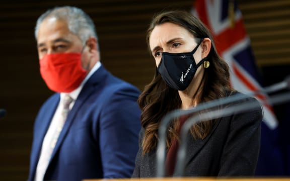 Minister Peeni Henare speaks to media while Prime Minister Jacinda Ardern looks on during a press conference at Parliament on September 02, 2021