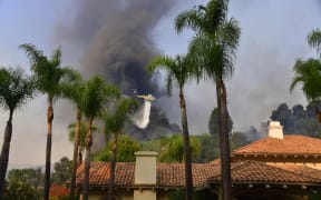 A helicopter drops water on fires threatening homes in Bel Air.