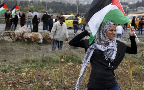 A Palestinian protester waves a Palestinian flag as she throws a stone during clashes with Israeli security forces near the Huwara checkpoint in the West Bank on Wednesday.