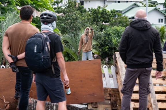 Masked residents watch an activist at the entrance to Tuband, in the Motor Pool district of Noumea on May 15, 2024, amid protests linked to a debate on a constitutional bill aimed at enlarging the electorate for upcoming elections of the overseas French territory of New Caledonia. One person was killed, hundreds more were injured, shops were looted and public buildings torched during a second night of rioting in New Caledonia, authorities said Wednesday, as anger over constitutional reforms from Paris boiled over. (Photo by Delphine Mayeur / AFP)