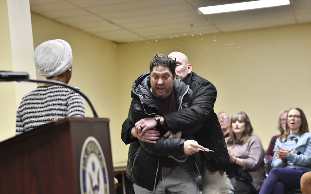 A man who sprayed U.S. Rep. Ilhan Omar (D-Minnesota) with an unknown substance is tackled during a town hall hosted by U.S. Rep. Ilhan Omar (D-Minn.) on January 27, 2026 in Minneapolis, Minnesota. Democratic U.S. Representative Ilhan Omar said she was targeted by a man while giving a speech late on January 27, and was sprayed with an unknown liquid from a syringe before being tackled by a security guard. scene. The men were ushered off the premises as Omar, a frequent target of attacks by President Donald Trump, continued to speak, saying: 