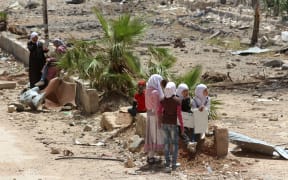 Syrian girls sit holding placards in the town of Daraya, southwest of central Damascus.