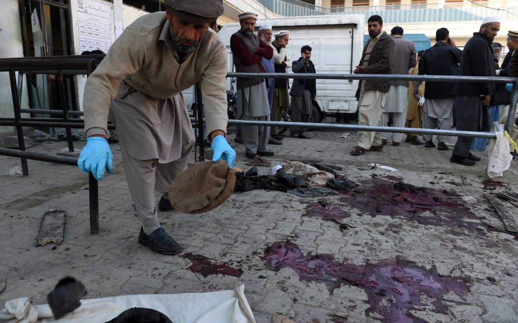 Pakistani security personnel collect evidence at the bomb blast site in Mardan.