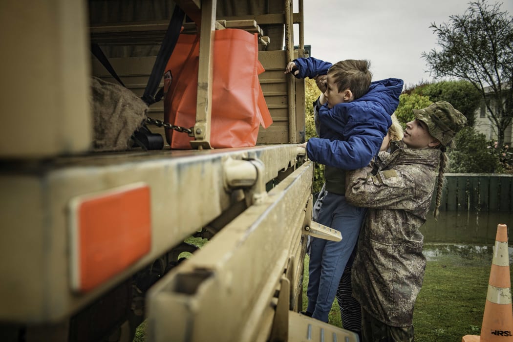 A soldier from Burnham helps a boy into an army truck amid Westport evacuations on Saturday.