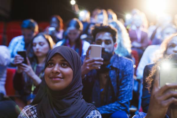 Smiling woman in hijab listening in audience.