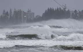 A person riding a jet ski attempts to tow surfboard riders amid record-breaking waves as the outer fringe of Tropical Cyclone Alfred started whipping eastern Australia, in Coolangatta on March 6, 2025. Tropical Cyclone Alfred was 285 kilometres (180 miles) east of busy Brisbane city after unexpectedly slowing above the Coral Sea overnight, government forecasts said. (Photo by David GRAY / AFP)