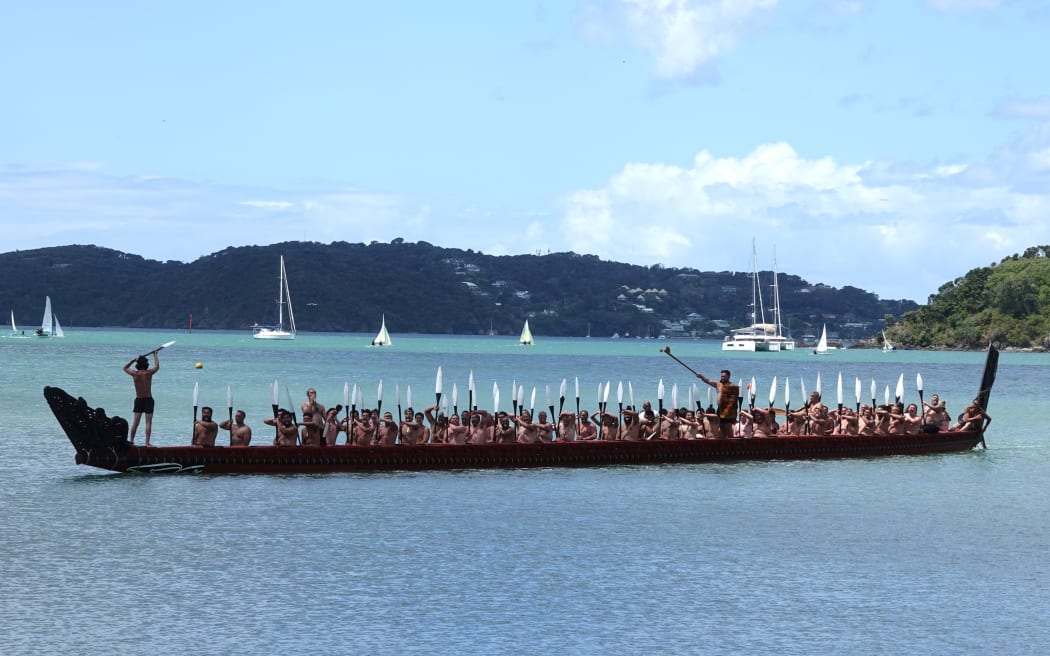 Kaikohe (paddlers) on the great waka Ngātokimatawhaorua perform a salute.