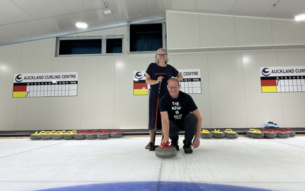 Picture shows two people posing at a curling rink.