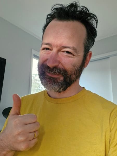Comedian and author Sam Smith wearing a yellow top and pulling a thumbs up.