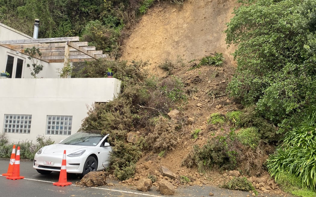 This slip at Mahina Bay near Eastbourne in Lower Hutt reached the edge of a busy arterial road and caught a Tesla in its path.