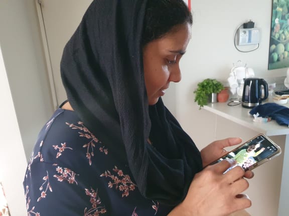 An photo of Gagandeep Kaur looking at an image of her daughter, Nimrat who is still in India.