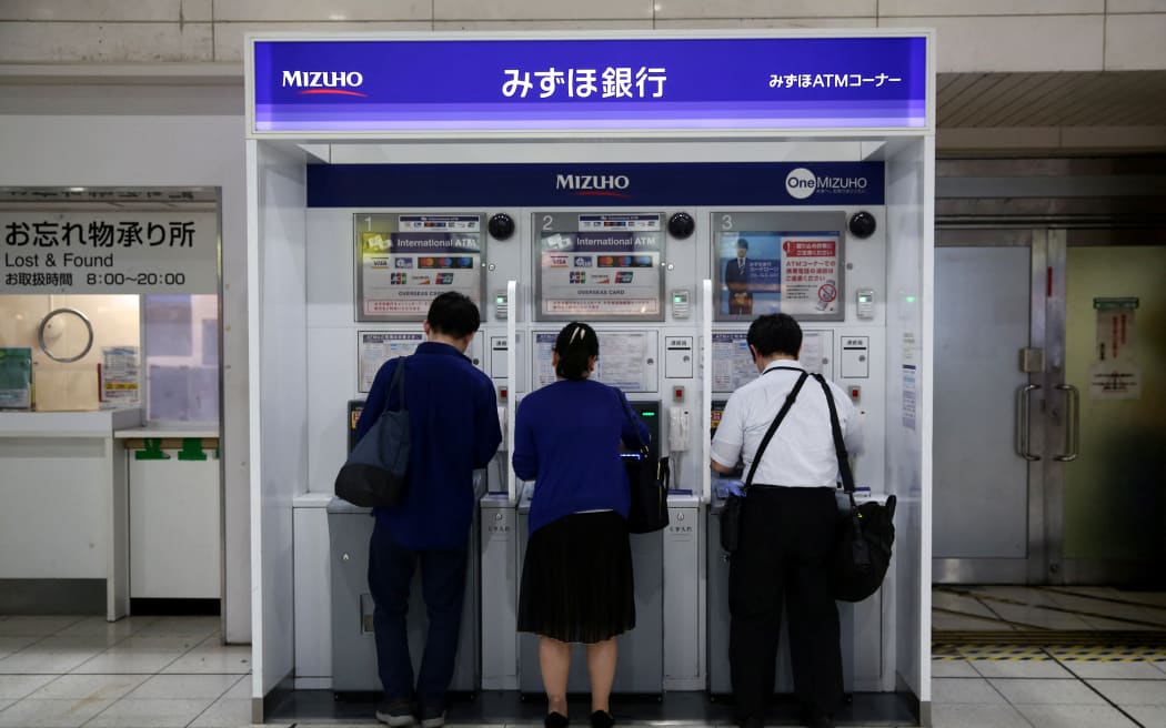 People use Mizuho bank automatic teller machines (ATM) at Shinagawa train station in Tokyo on July 18, 2019.