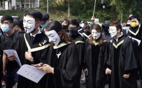 Students from the Chinese University of Hong Kong (CUHK), wearing graduation gowns and and masks, take part in a protest march in memory of the pro-democracy demonstrations at CUHK a year ago,  in the Shatin area of Hong Kong on November 19, 2020.