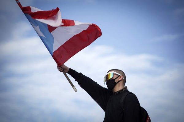 Puerto Rican reggaeton singer Bad Bunny waves a Puerto Rican flag as he takes part of a demonstration demanding Governor Ricardo Rossello's resignation in San Juan, Puerto Rico on July 17, 2019. Thousands marched in Puerto Rico for a fifth day on Wednesday demanding the resignation of Governor Ricardo Rossello, following corruption accusations and the leak of text chats in which he made sexist and homophobic remarks.