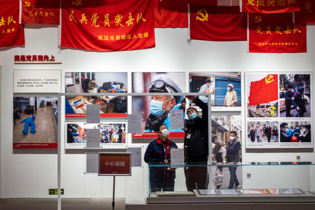 People wearing masks work at an exhibition on the fight against Covid-19, at Wuhan Parlor Convention Center.