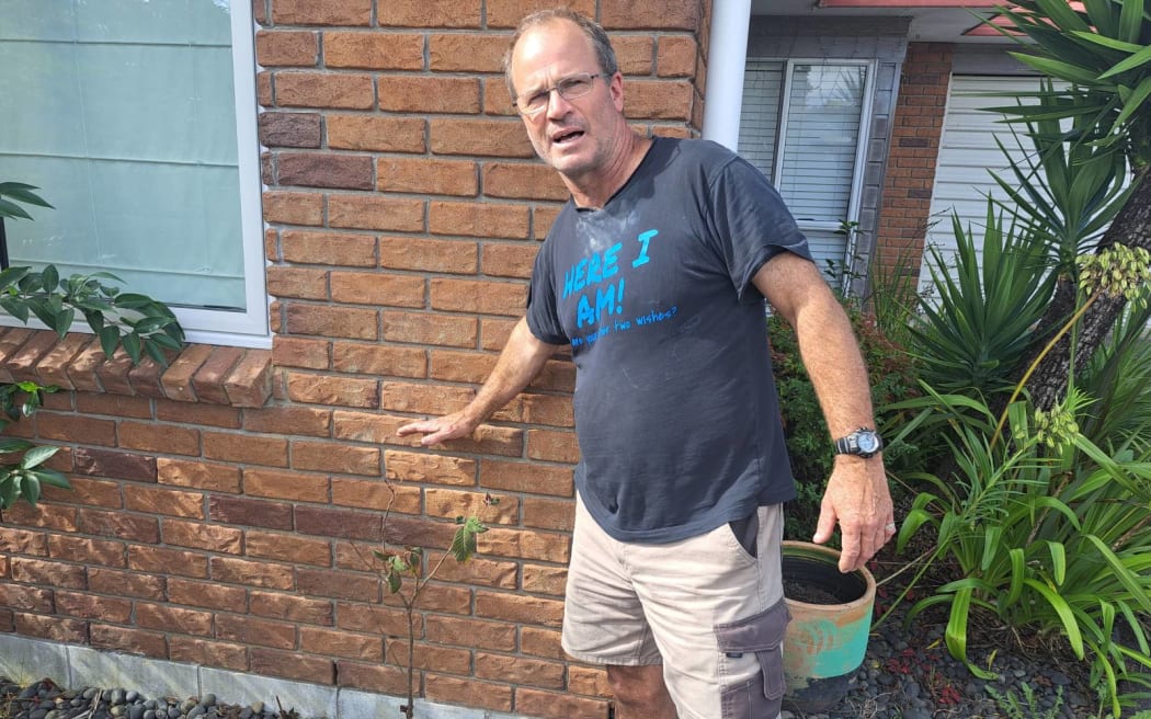 Glenn Whittington points to water line during flooding.