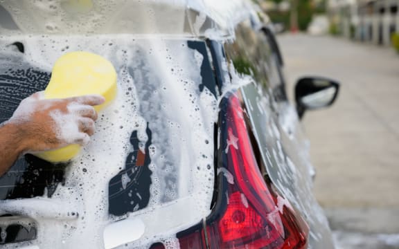 Man cleaning washing car with sponge and foam