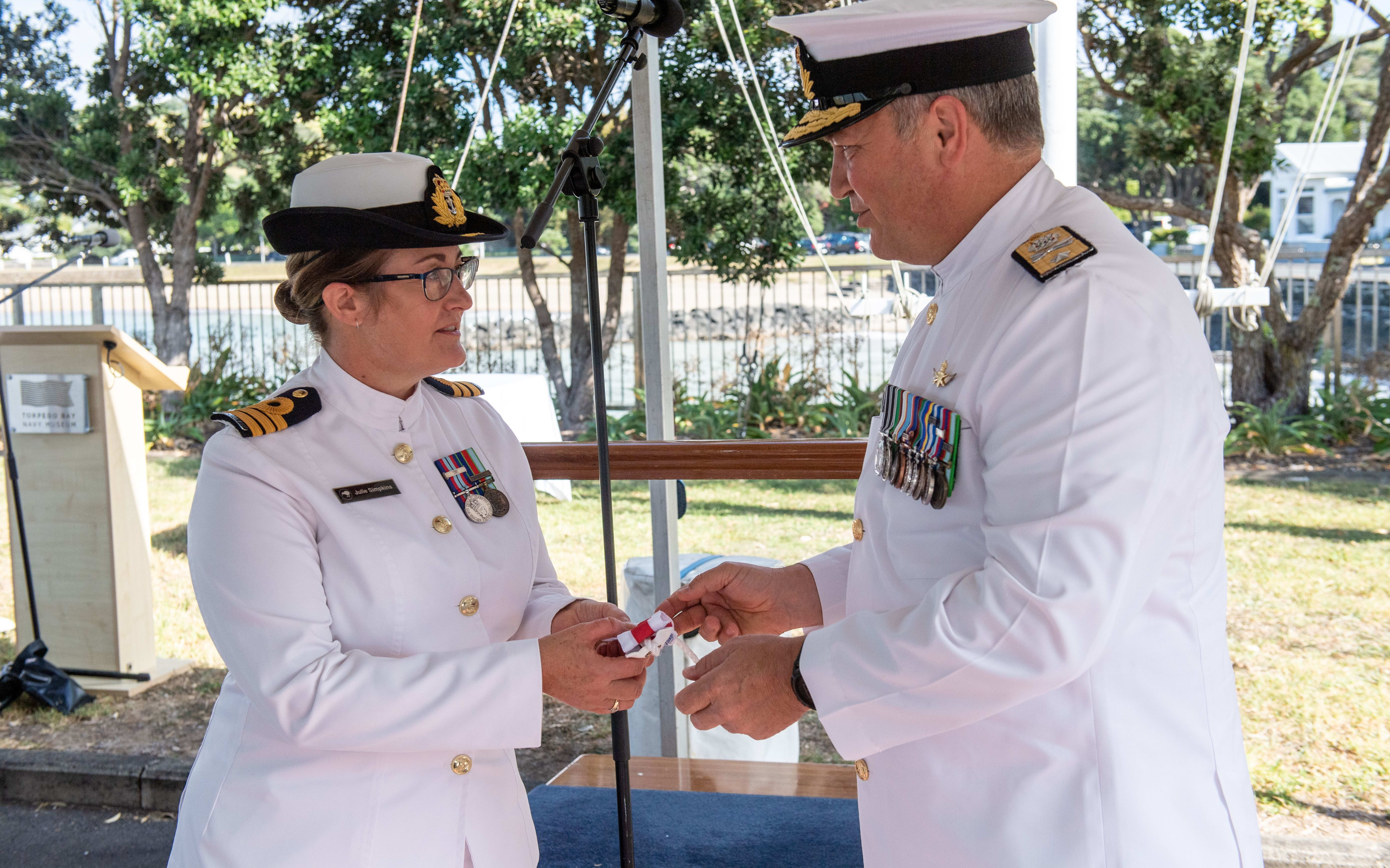 Deputy Chief of Navy, Commodore Shane Arndell, right, hands over the Commissioning Pennant to new HMNZS Philomel Commanding Officer, Commander Julie Simpkins