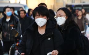 People wearing masks head for Beijing Station in Beijing, China on 20 January, ahead of China's Lunar New Year holiday. Tens of thousands of people travel and visit overseas during the holiday.