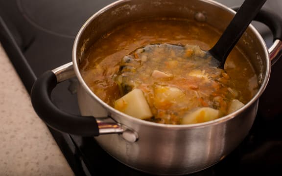 Chicken soup in a saucepan on the stove.
