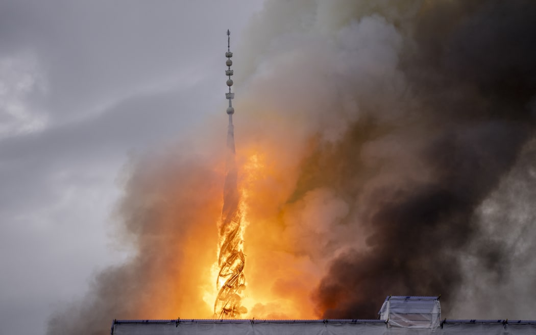 Plumes of smoke billow from the Dragon Spire of the Stock Exchange building which is on fire in central Copenhagen, Denmark on April 16, 2024. A huge fire tore through Copenhagen's 17th-century former stock exchange, toppling the historic building's landmark spire in front of horrified and emotional witnesses. Amid flames and black smoke, the 54-metre (180-foot) spire crashed into the street below the the Borsen building, which had been undergoing renovation. (Photo by Ida Marie Odgaard / Ritzau Scanpix / AFP) / Denmark OUT