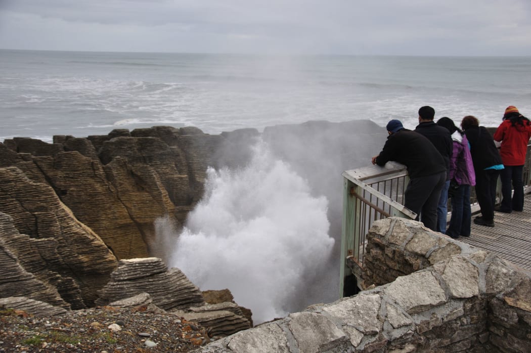 Tourists enjoy the main blowhole in action at the Pancake Rocks, Punakaiki