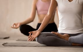 Two beautiful diverse yogi girls contemplating, doing yoga Padmasana exercise, Lotus pose, working out indoor, close up, mixed race female students training at yoga studio. Well being, wellness concept