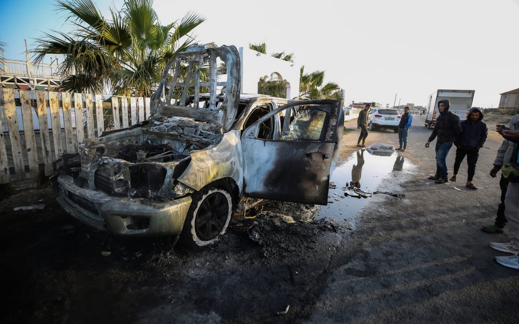 Palestinians are standing next to a vehicle in Deir Al-Balah, in the central Gaza Strip, on April 2, 2024, where employees from the World Central Kitchen (WCK), including foreigners, were killed in an Israeli airstrike, according to the NGO. The Israeli military is stating that it is conducting a thorough review at the highest levels to understand the circumstances of this ''tragic'' incident, amid the ongoing conflict between Israel and Hamas. (Photo by Yasser Qudihe / Middle East Images / Middle East Images via AFP)