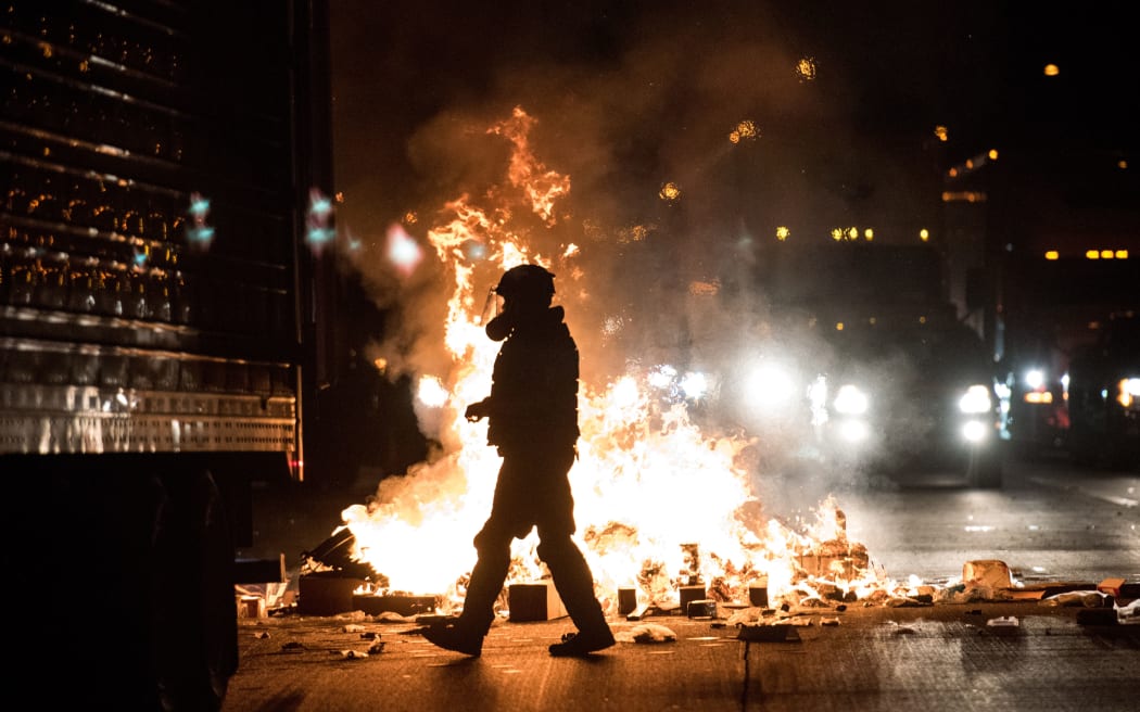 A police officer in riot gear walks past a fire on the I-85 during protests in the early hours of the morning in Charlotte, North Carolina.
