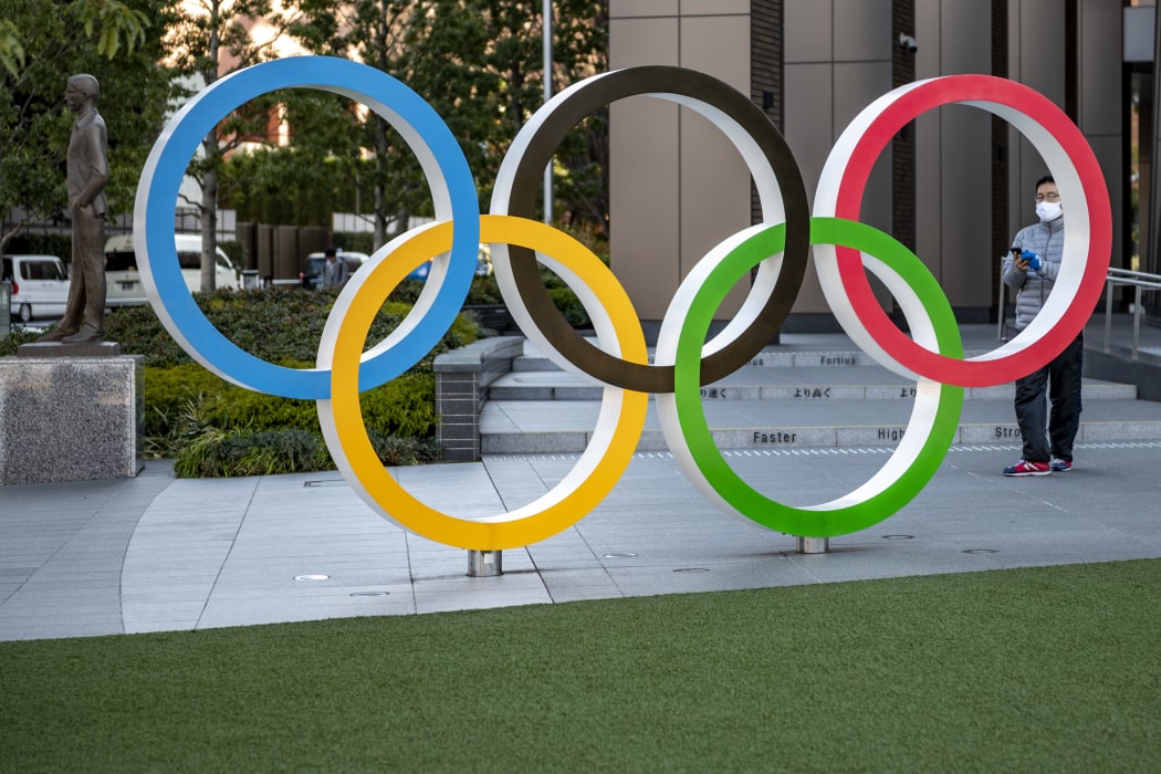 This picture taken on January 20, 2021 shows a visitor taking photos of the Olympic rings outside the Olympic Museum in Tokyo.