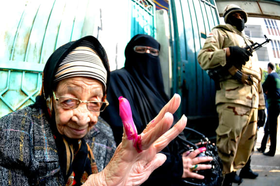 A woman shows her ink-stained finger after voting in Alexandria.