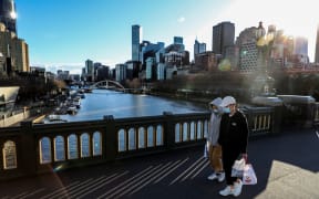 Pedestrians wearing face masks walk through Melbourne's Southbank on 16 July 2021, following a fresh Covid-19 lockdown.