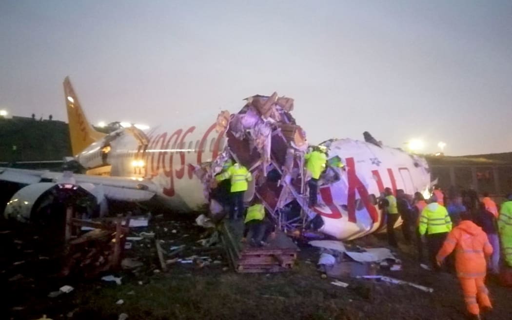 Officials work around the site after a passenger plane skidded off the runway in Istanbul Sabiha Gokcen International Airport, breaking into two, on 5 February 2020