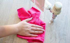 Female hand with rag cleaning water from heating radiator