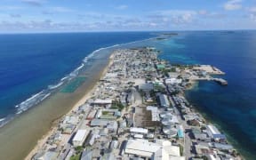 A drone photo shows the southern portion of Ebeye Island with the Kwajalein Army base headquarters island in the distance. The island is currently experiencing ongoing power outages for lack of generators.