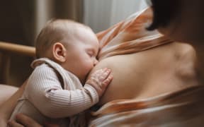 Woman comfortably breastfeeding her baby in a cozy room