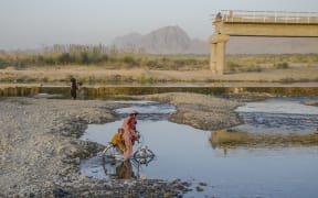 A boy and a child cross a riverbed on a bicycle in Kandahar, Afghanistan, 23 September 2021.