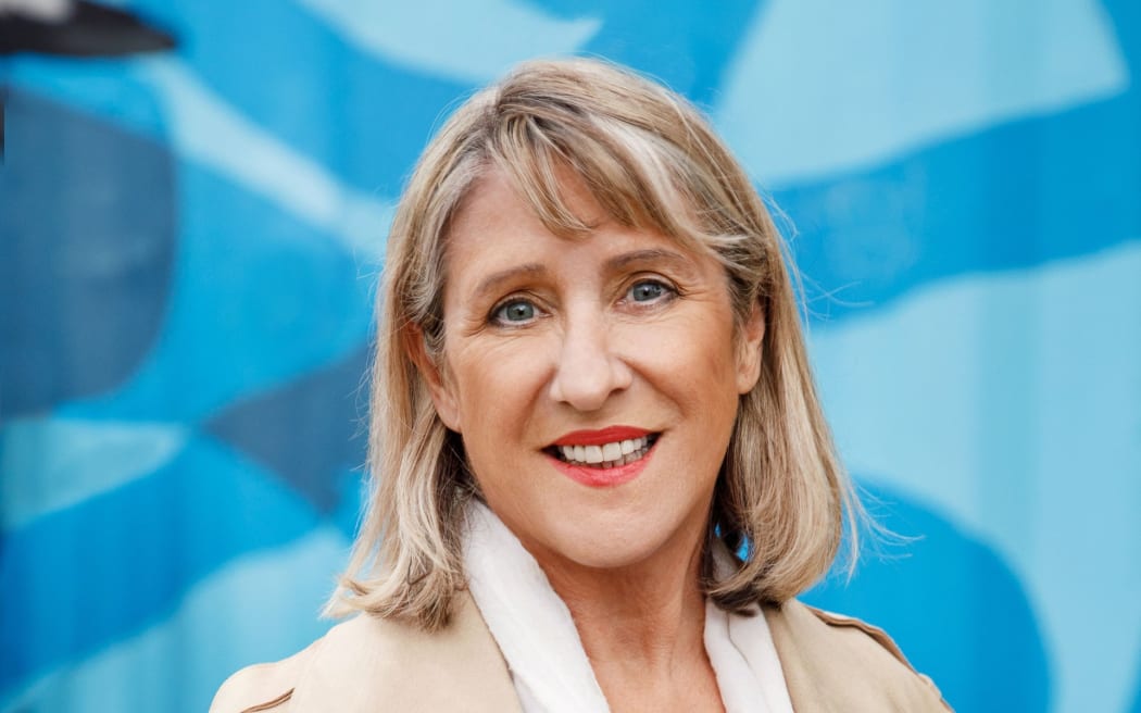 Woman standing in mac with white scarf draped around neck
