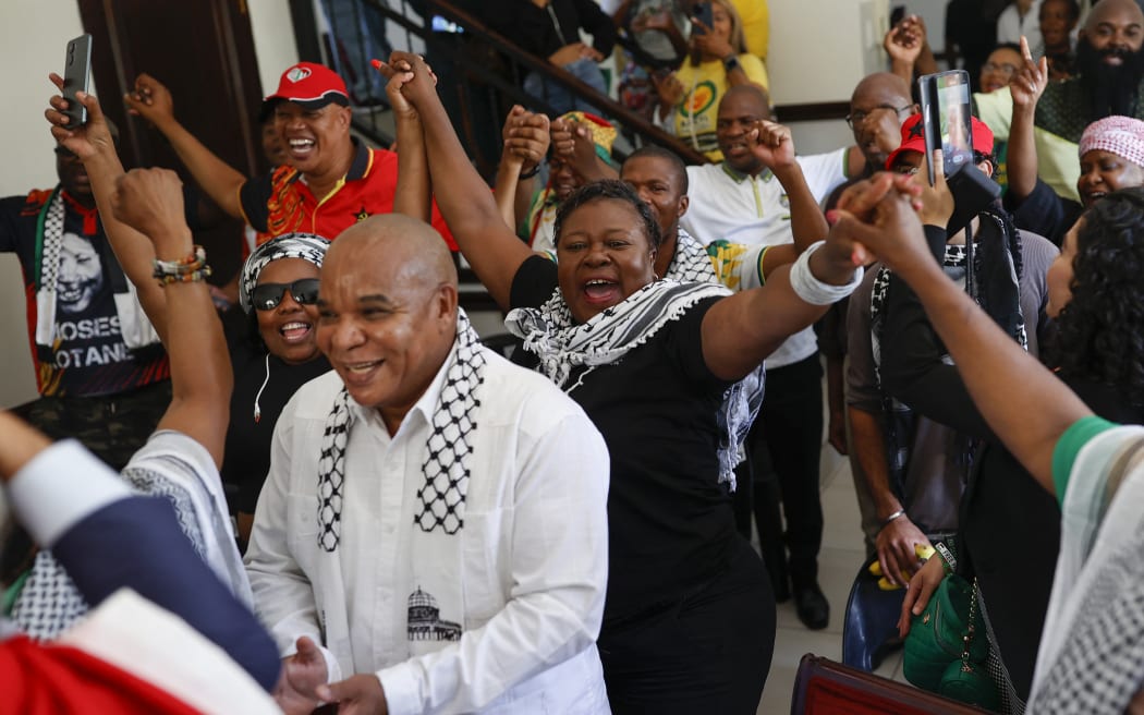 Pro-Palestinian supporters react in celebration after watching the International Court of Justice (ICJ) delivering its decision following a hearing of the case against Israel brought by South Africa in The Hague at the Embassy of Palestine in Pretoria on January 26, 2024. South African lawyers presented their case at the UN's top court in The Hague, where South Africa lodged an urgent appeal to force Israel to "immediately suspend" its military operations in Gaza. The International Court of Justice (ICJ) ruled on January 26, 2024 that it has jurisdiction over the genocide case. (Photo by Phill Magakoe / AFP)