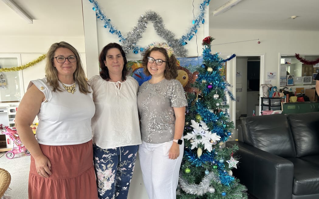 Picture of three women, next to a Christmas tree.