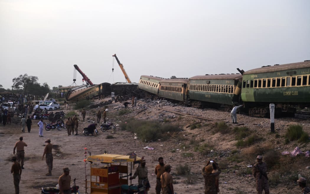 Security personnel and volunteers inspect the accident site following the derailment of a passenger train in Nawabshah on August 6, 2023. At least 28 people were killed August 6 when an express train derailed in southern Pakistan, the railway minister said, with an emergency declared at local hospitals struggling to deal with with dozens of injured. (Photo by ASIF HASSAN / AFP)