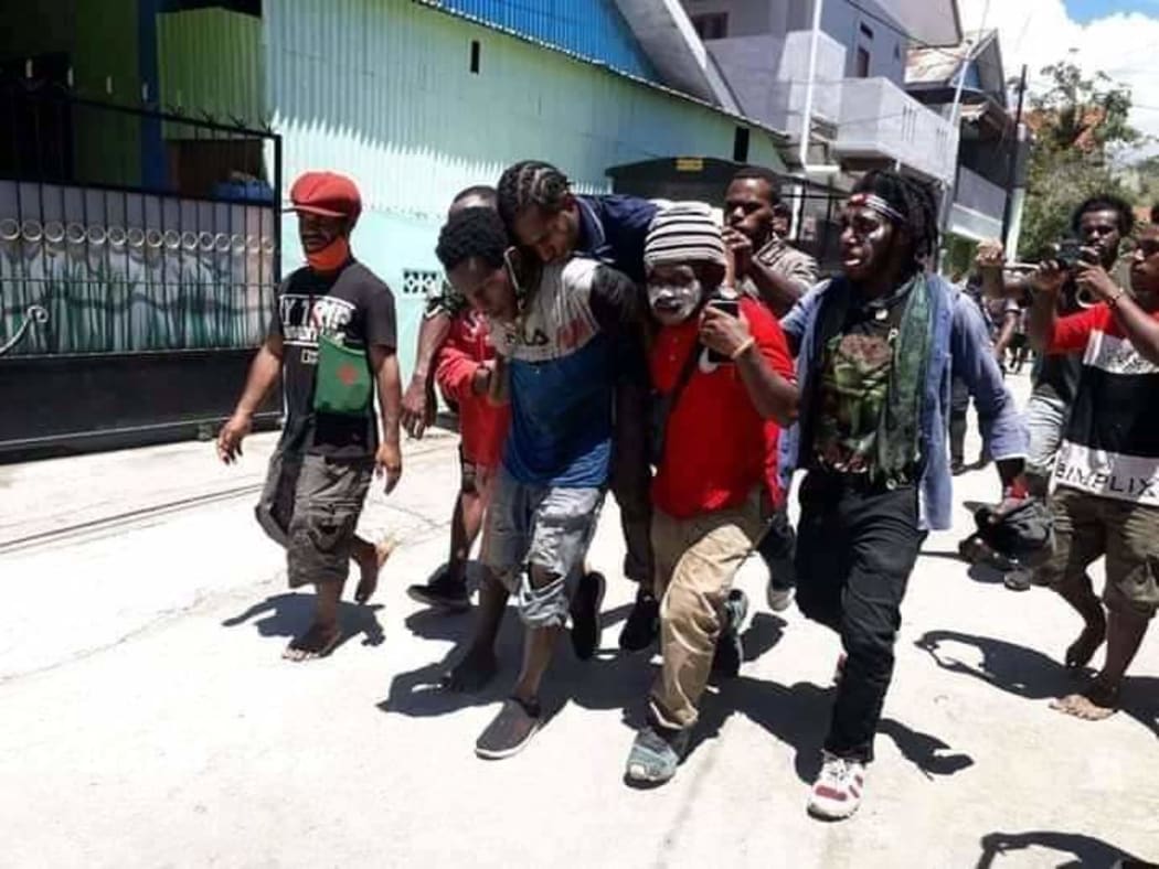 West Papuan students carry a wounded fellow demonstrator after security forces came to disband their rally, Waena, 27 October, 2020